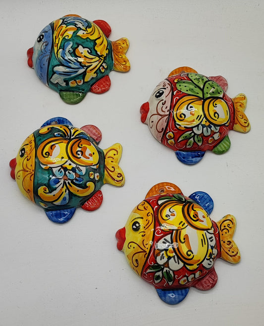 Four glossy hand-painted Sicilian ceramic fish in blue, turquoise, yellow, white and red on a white background