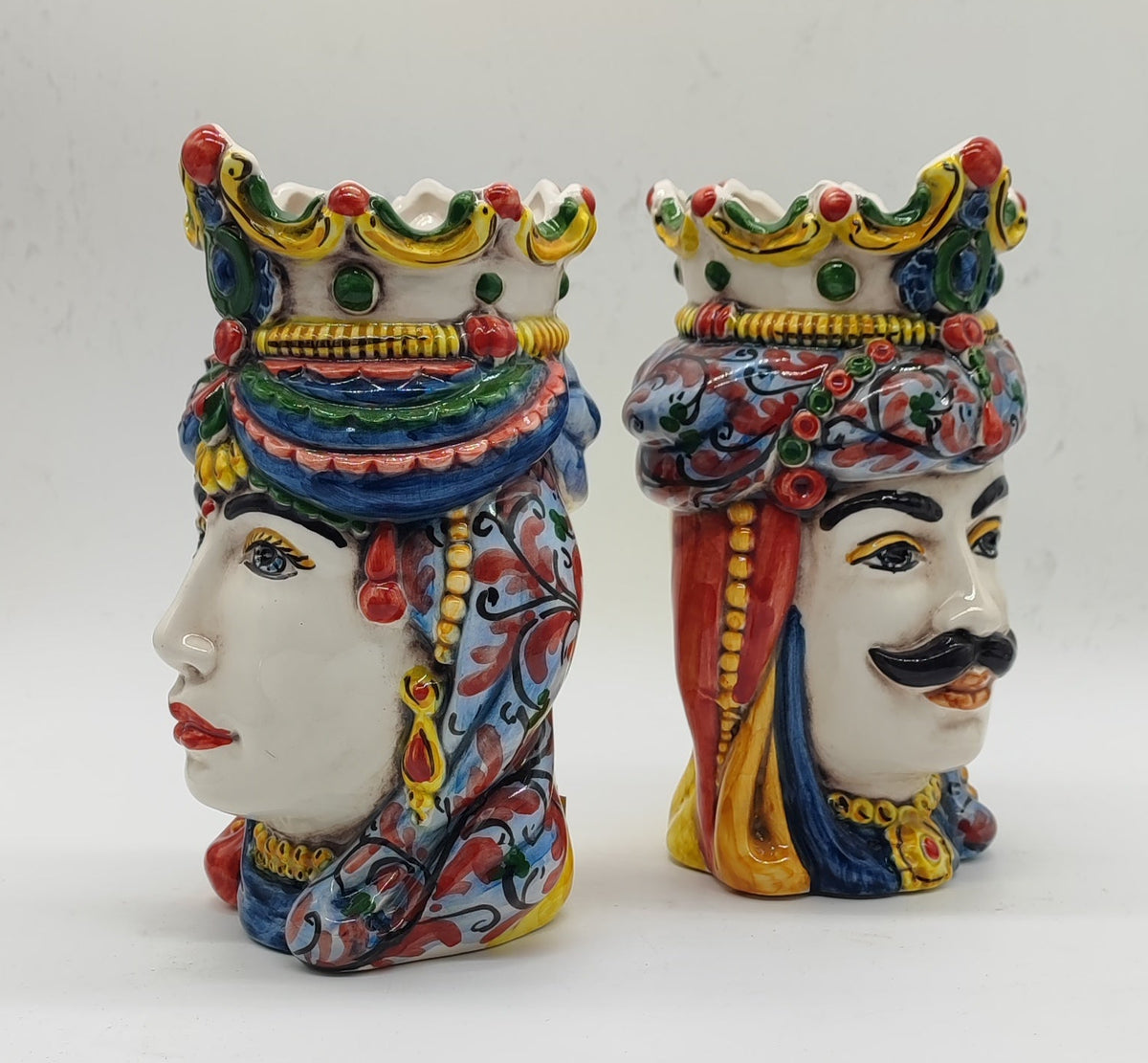 Side profiles of Donna and Maschio Sicilian ceramic Moorish Heads featuring colorful hand-painted crowns and ornamental details.