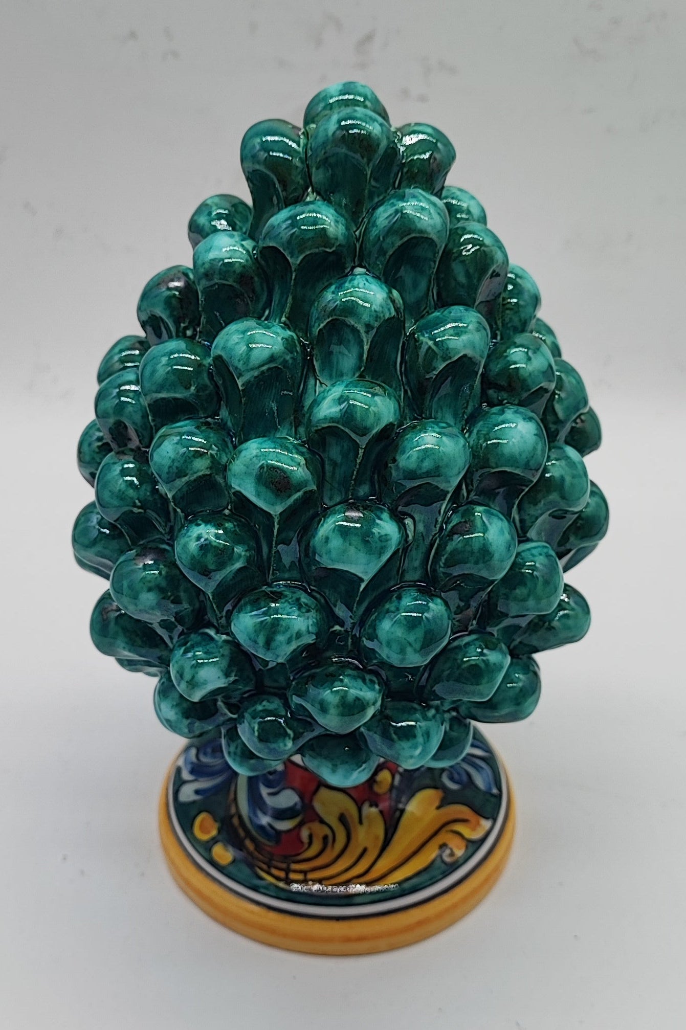 Green Sicilian ceramic pine cone displayed in an elegant rustic country-style living room