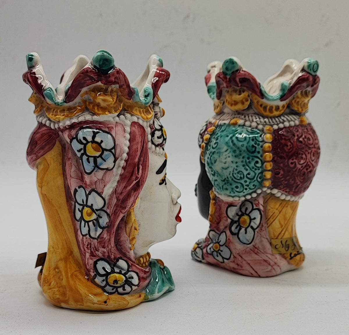 Close-up of floral motifs, raised crown details and glossy glaze on Sicilian ceramic Moorish heads.