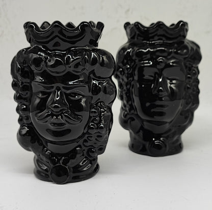 Two glossy black Sicilian Moorish head vases on a stone terrace with lemons and a sea view