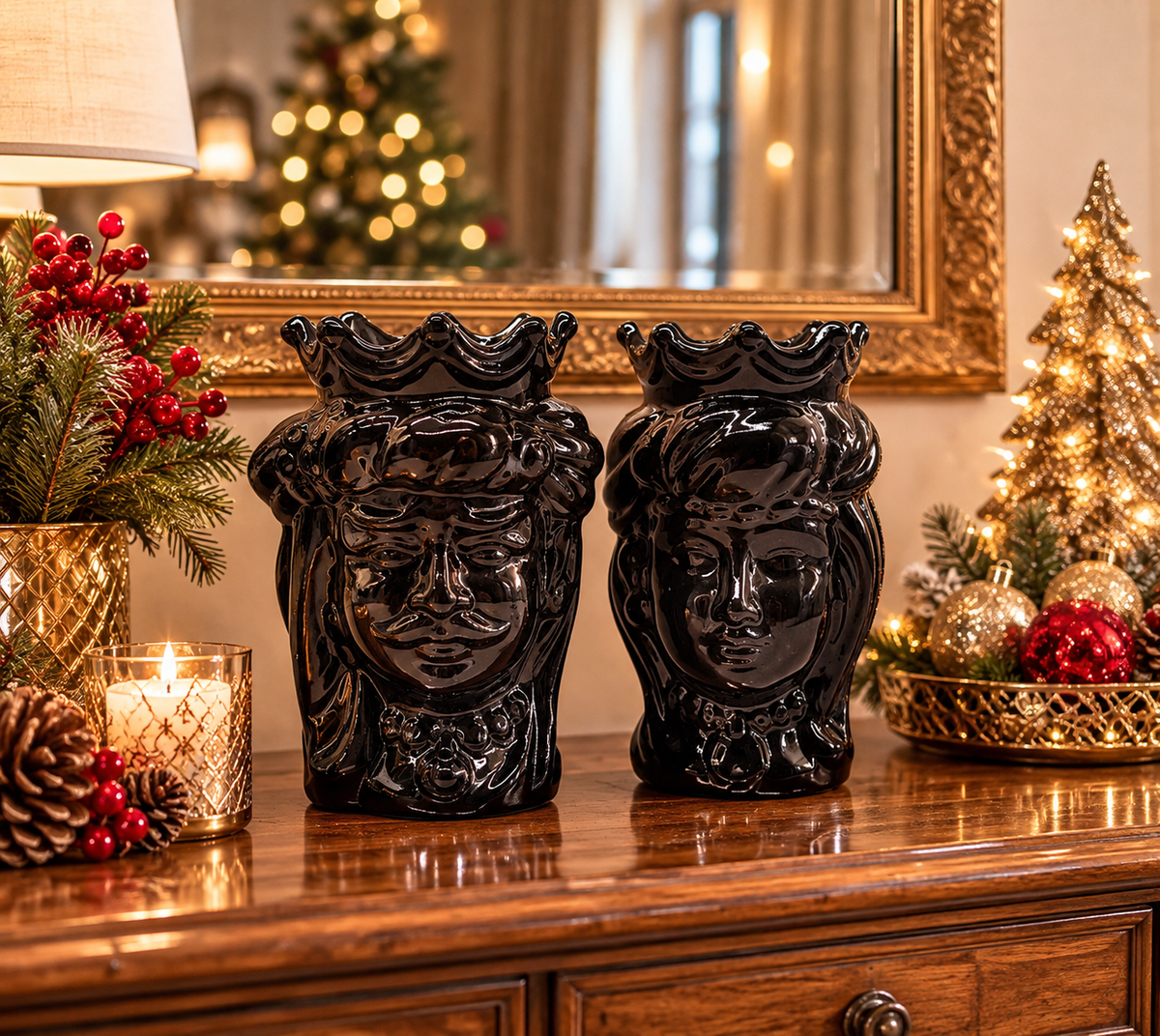 Glossy black Sicilian Moorish Heads ceramic couple displayed on an elegant Christmas dresser with festive gold decorations.