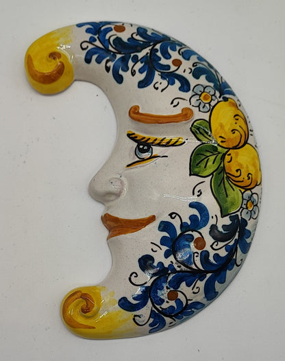 Blue and yellow Sicilian ceramic moon displayed on an Italian terrace with lemon and orange trees