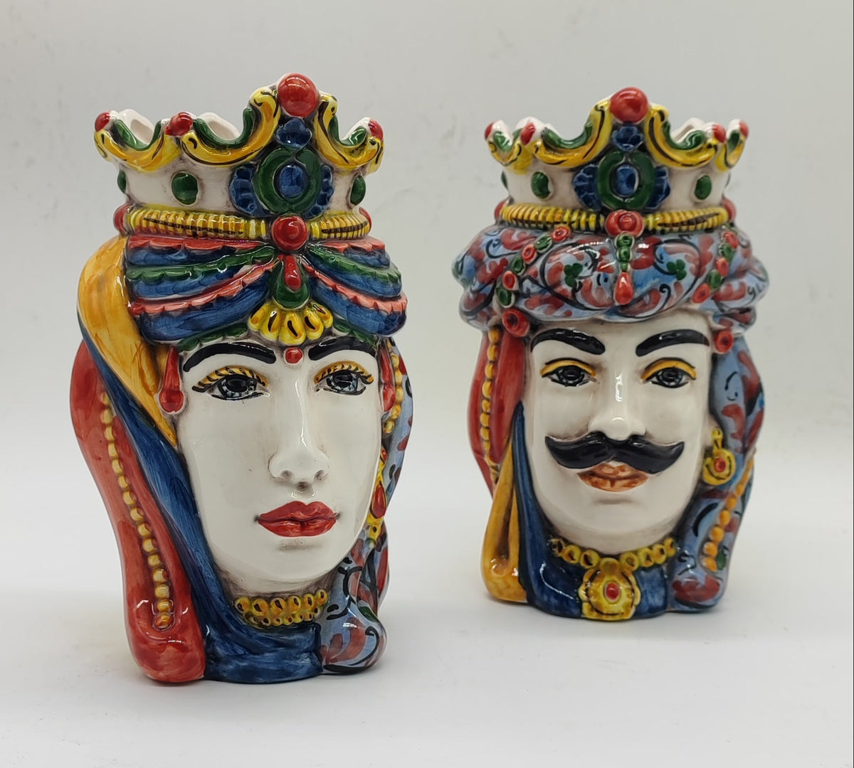 Front view of colorful Sicilian Teste di Moro ceramic heads with decorative crowns, female and male matching set.