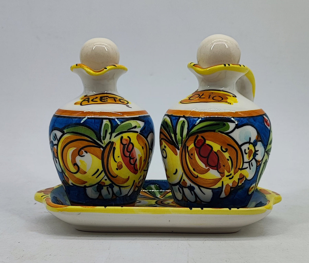 Caltagirone-style ceramic olive oil and vinegar bottles decorated with colorful Mediterranean fruit