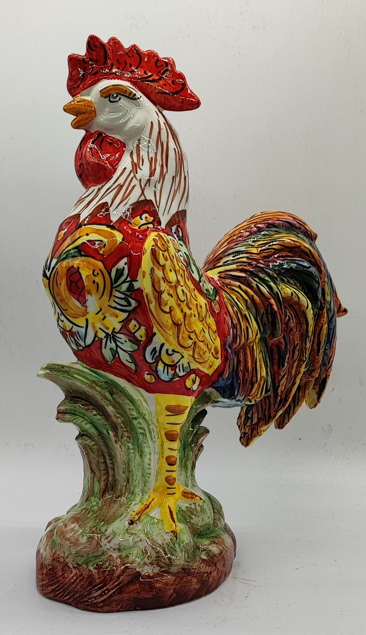 Right-facing view of the Sicilian ceramic rooster showing its painted wing, white neck and sculpted base