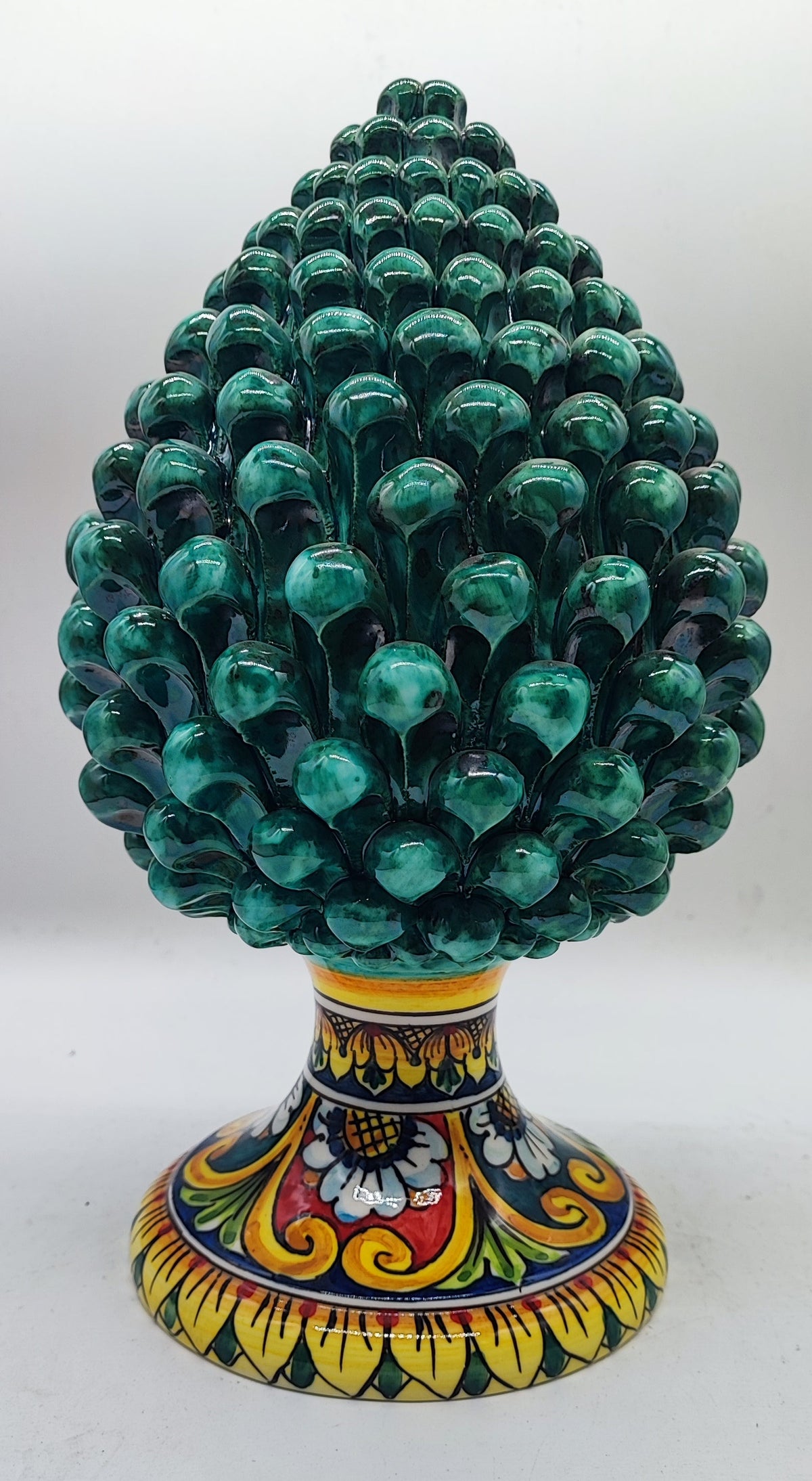Emerald green Sicilian ceramic pine cone styled with festive greenery and warm Christmas decorations.
