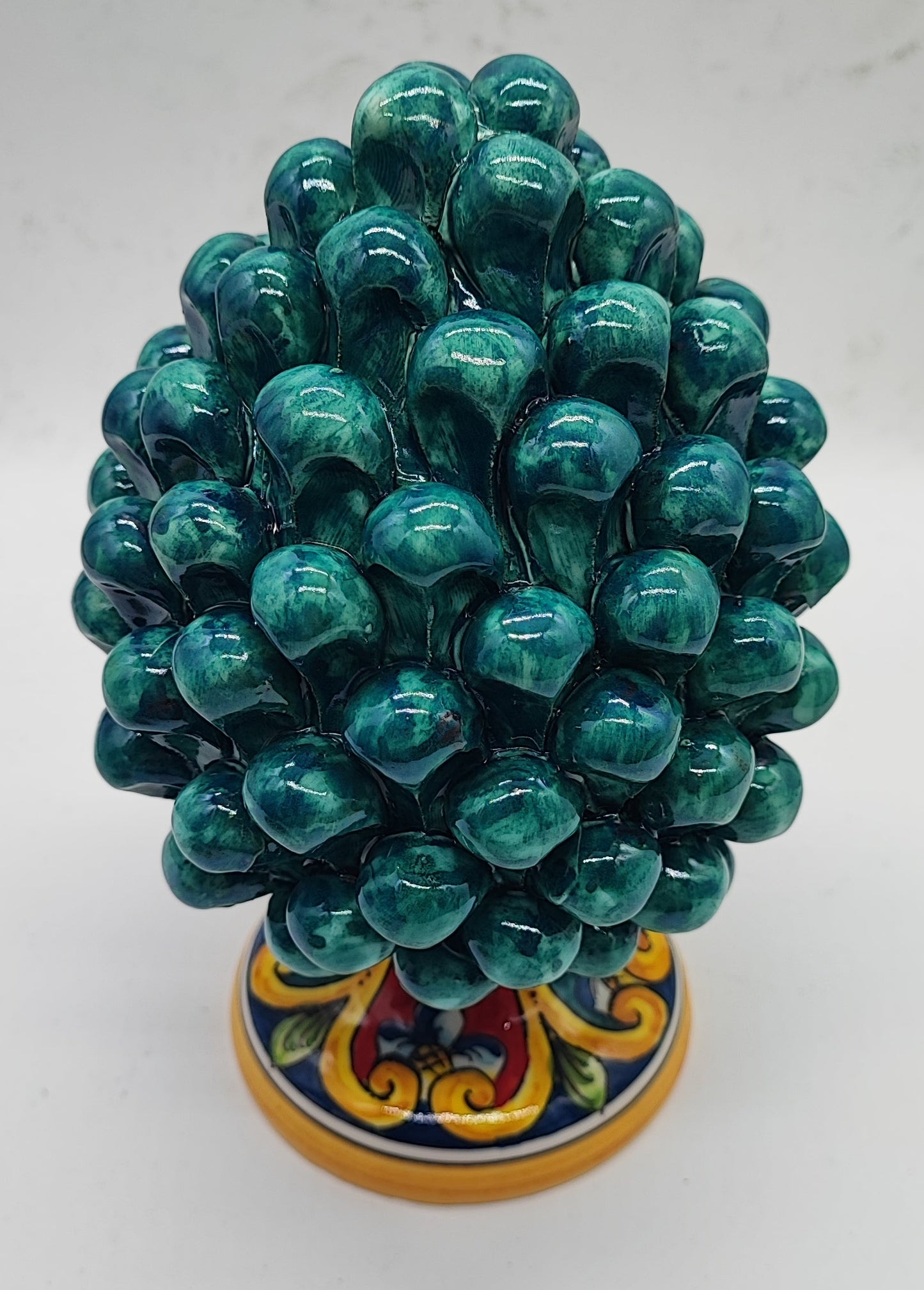 Emerald green Sicilian ceramic pine cone displayed on a wooden dresser in an American country home