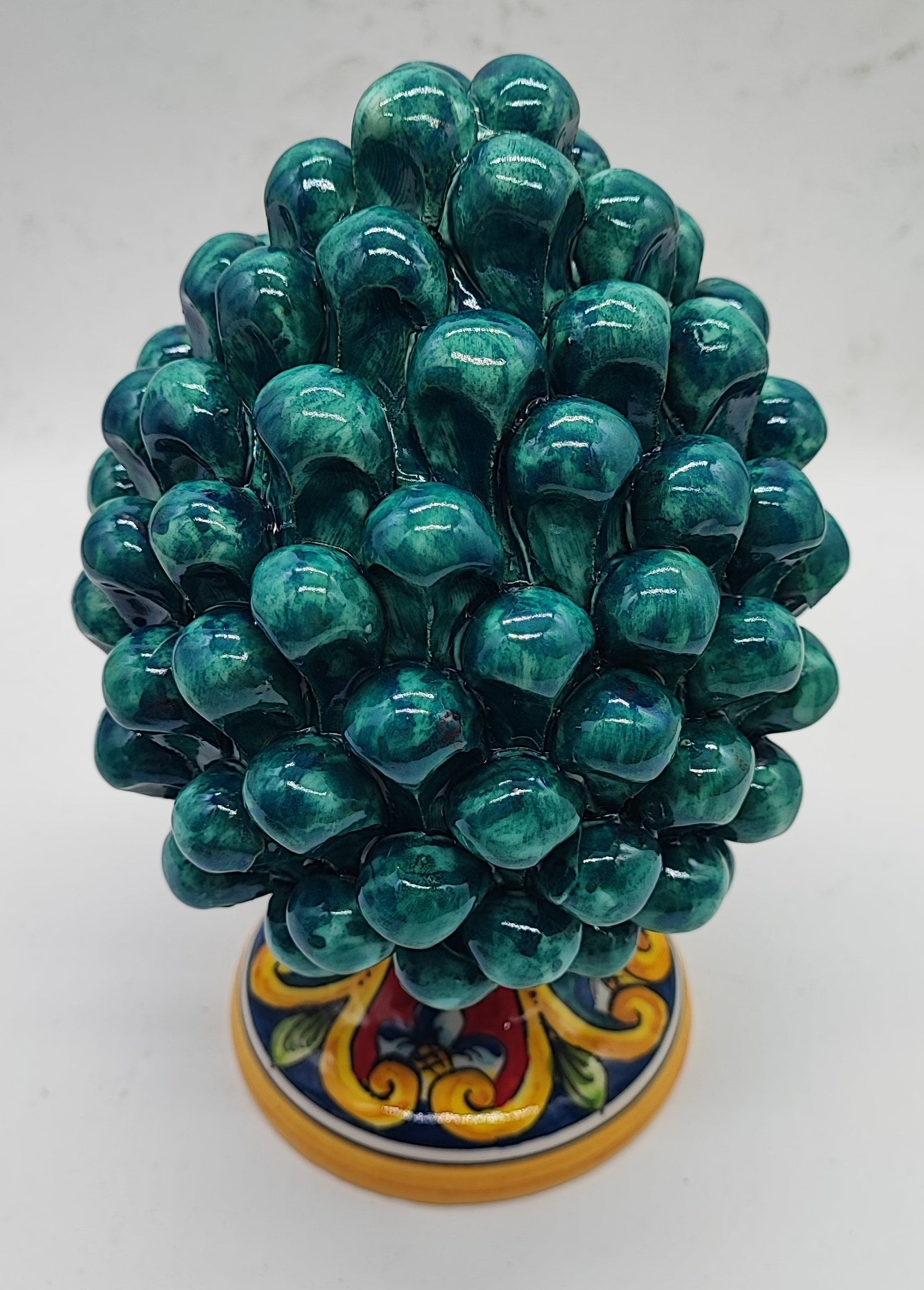 Emerald green Sicilian ceramic pine cone displayed on a wooden dresser in an American country home