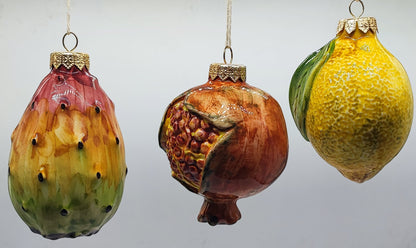 Authentic hand-painted Sicilian ceramic prickly pear, pomegranate and lemon Christmas decorations displayed together on a white background.