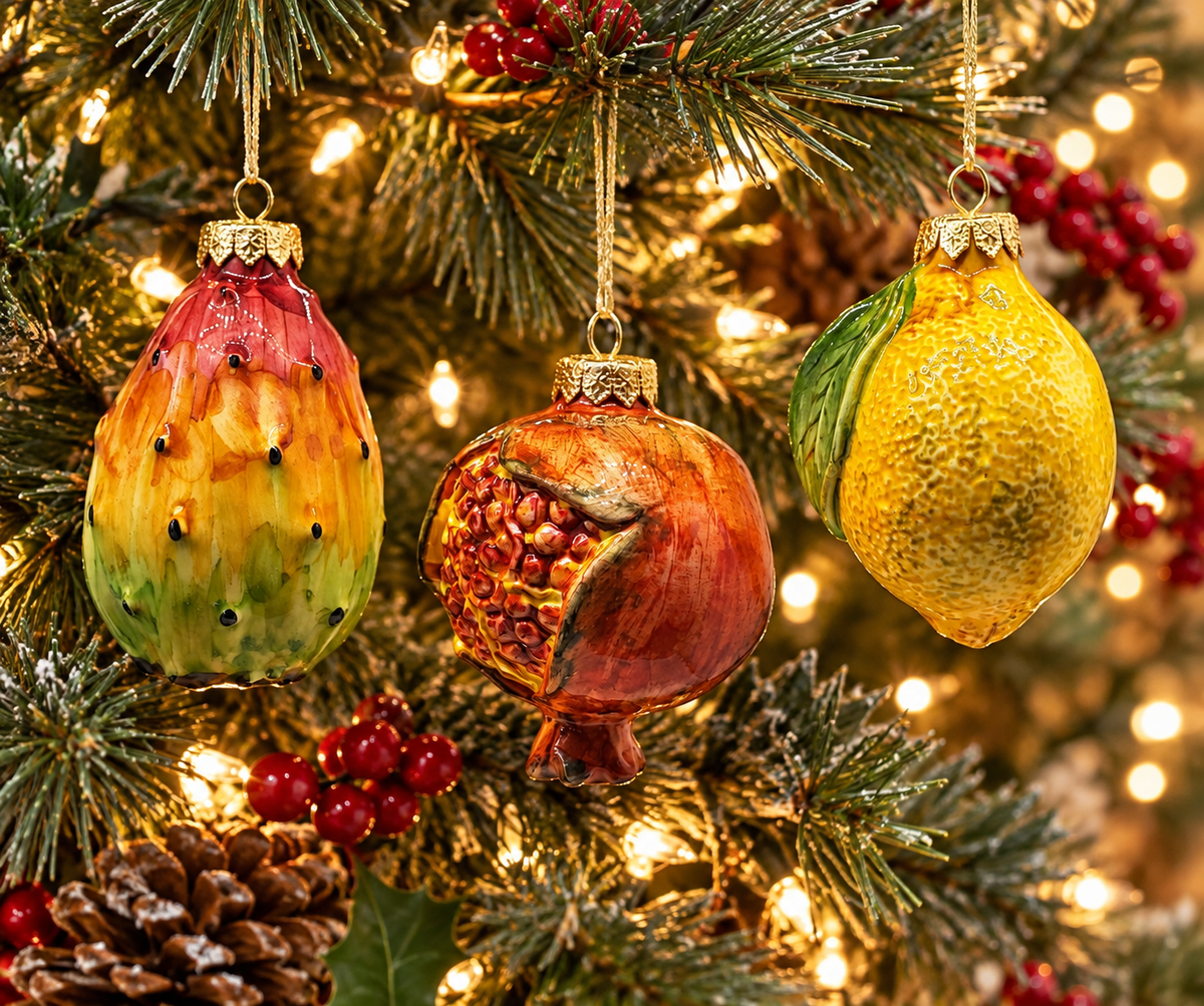 Alt Text: Three handmade Sicilian ceramic Christmas fruit ornaments featuring prickly pear, pomegranate and lemon hanging on a festive Christmas tree.