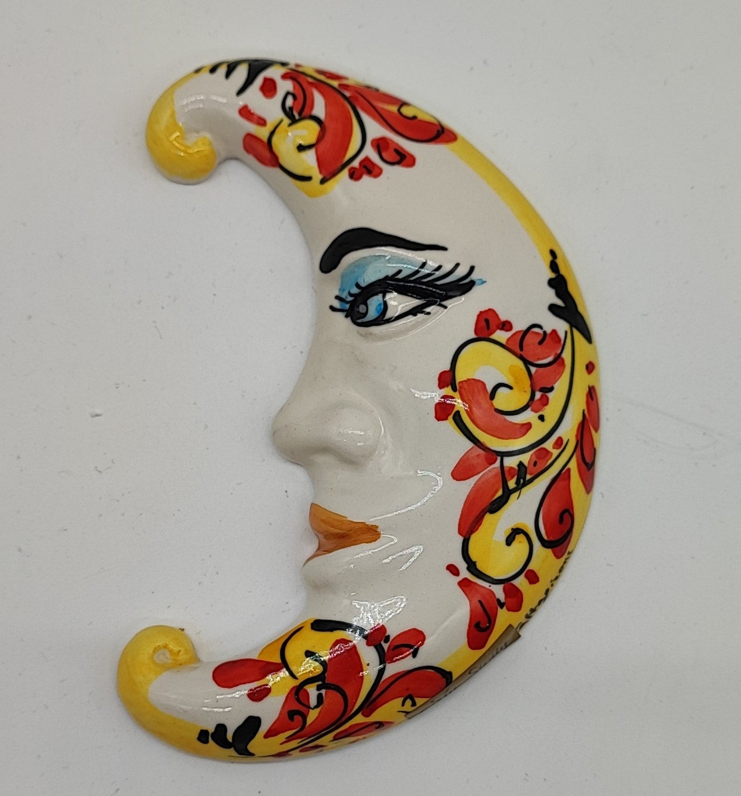 Red and yellow Sicilian ceramic moon measuring 16 cm tall on a flower-filled Italian terrace