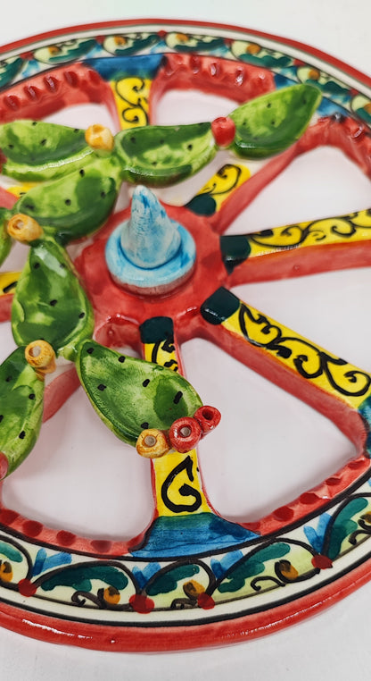 Person holding a colourful ceramic Sicilian cart wheel with raised green prickly pears. Text shows a diameter of 20 cm, 7.9 inches.