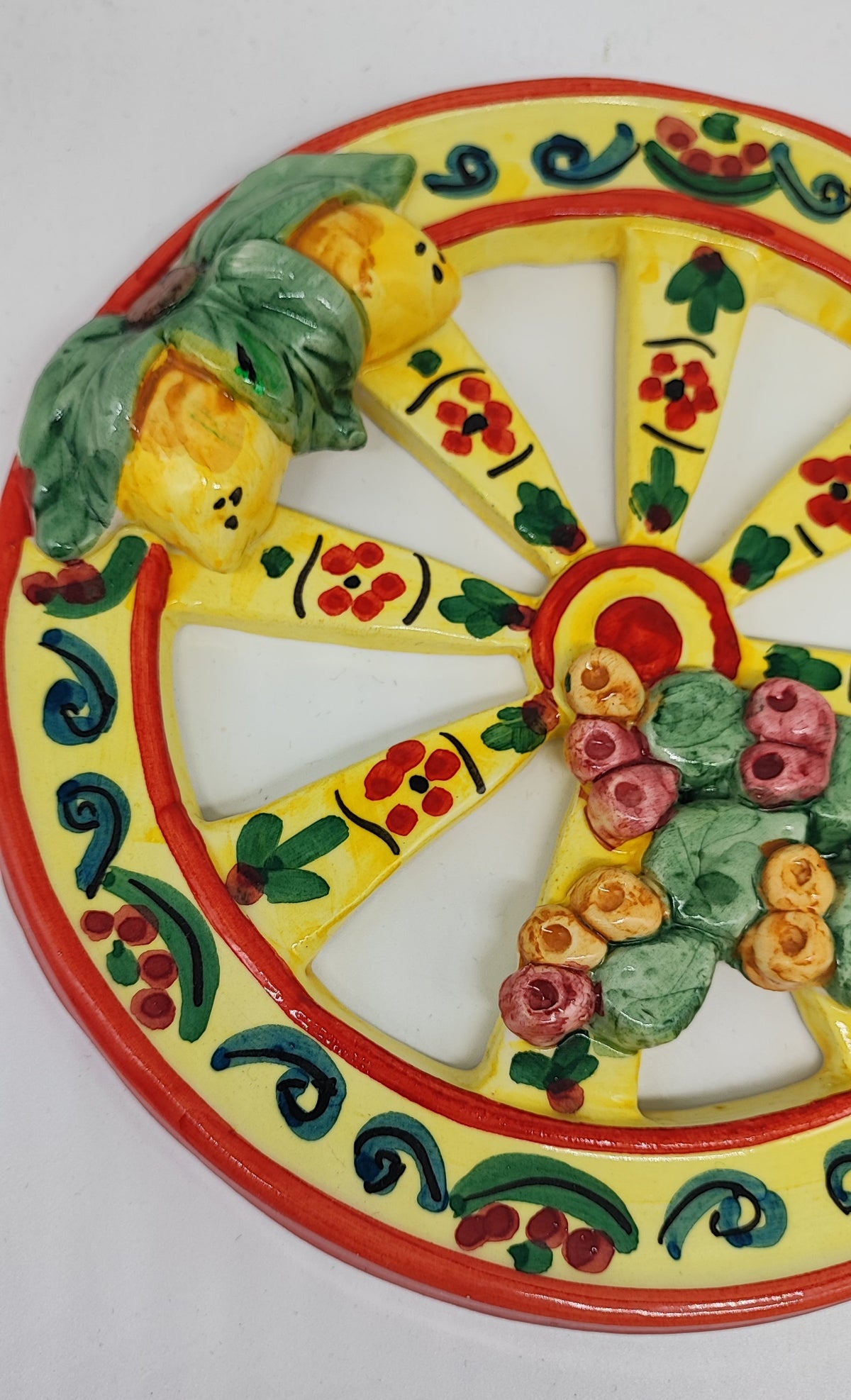 Yellow Sicilian ceramic cart wheel with raised lemons, green leaves and prickly pears, 21 cm in diameter.