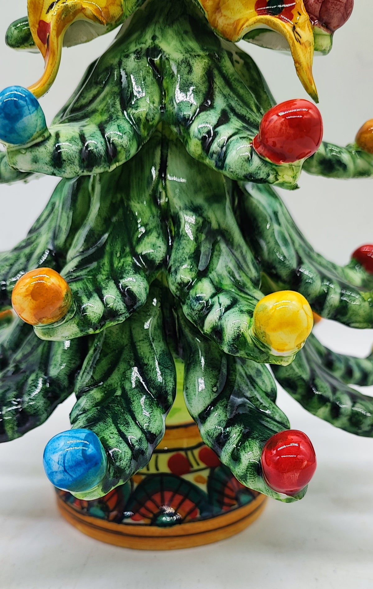 Close-up of colorful glazed ceramic ornaments and hand-painted branches on a Sicilian Christmas tree.