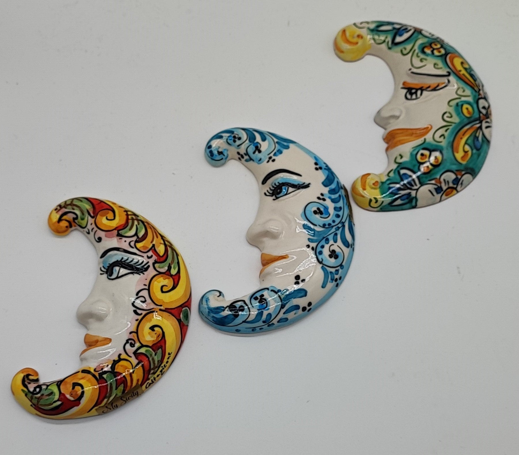 Three Sicilian ceramic moons displayed on an Italian terrace with lemons, oranges, flowers and Mediterranean sea view