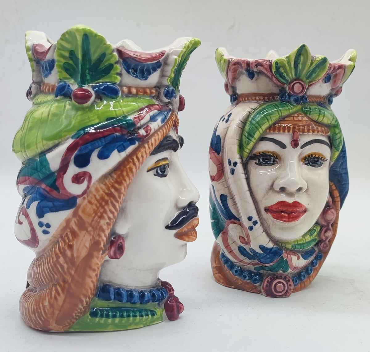 Colorful Sicilian Teste di Moro pair styled with lemons and Mediterranean decor overlooking the sea.
