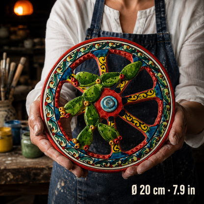 Angled detail of green ceramic cactus pads with yellow and red fruits beside the wheel's cream border with green scroll patterns.