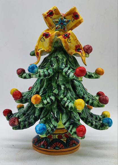 Front view of a handcrafted green ceramic Christmas tree with colorful baubles and a floral yellow bow.