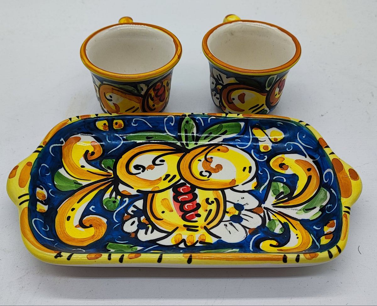 Detailed view of traditional Sicilian majolica espresso cups and ceramic tray, featuring vibrant yellow, blue, green and orange hand-painted decorations.