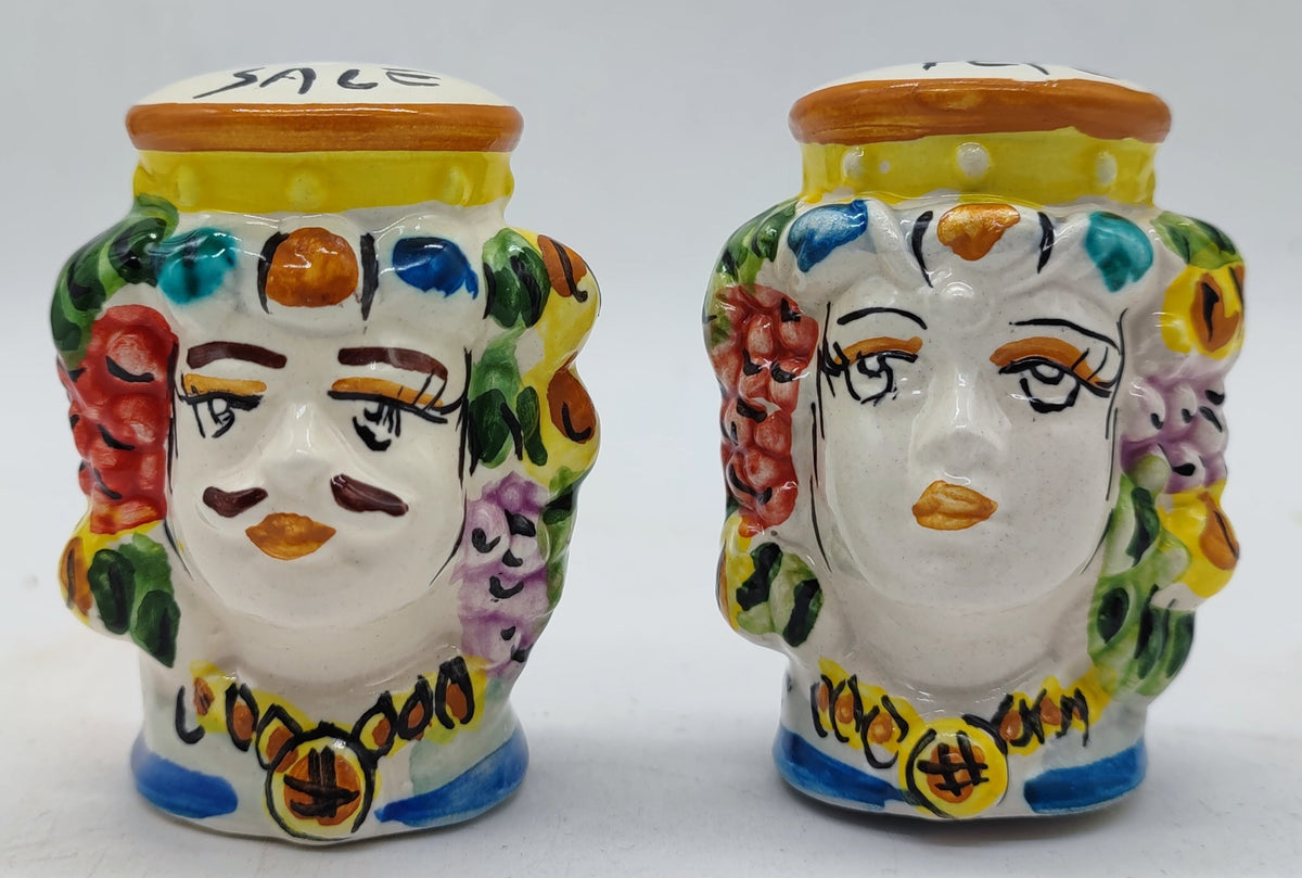Close-up of traditional Sicilian Teste di Moro salt and pepper shakers with expressive hand-painted faces and floral details.
 Kopiuj ALT