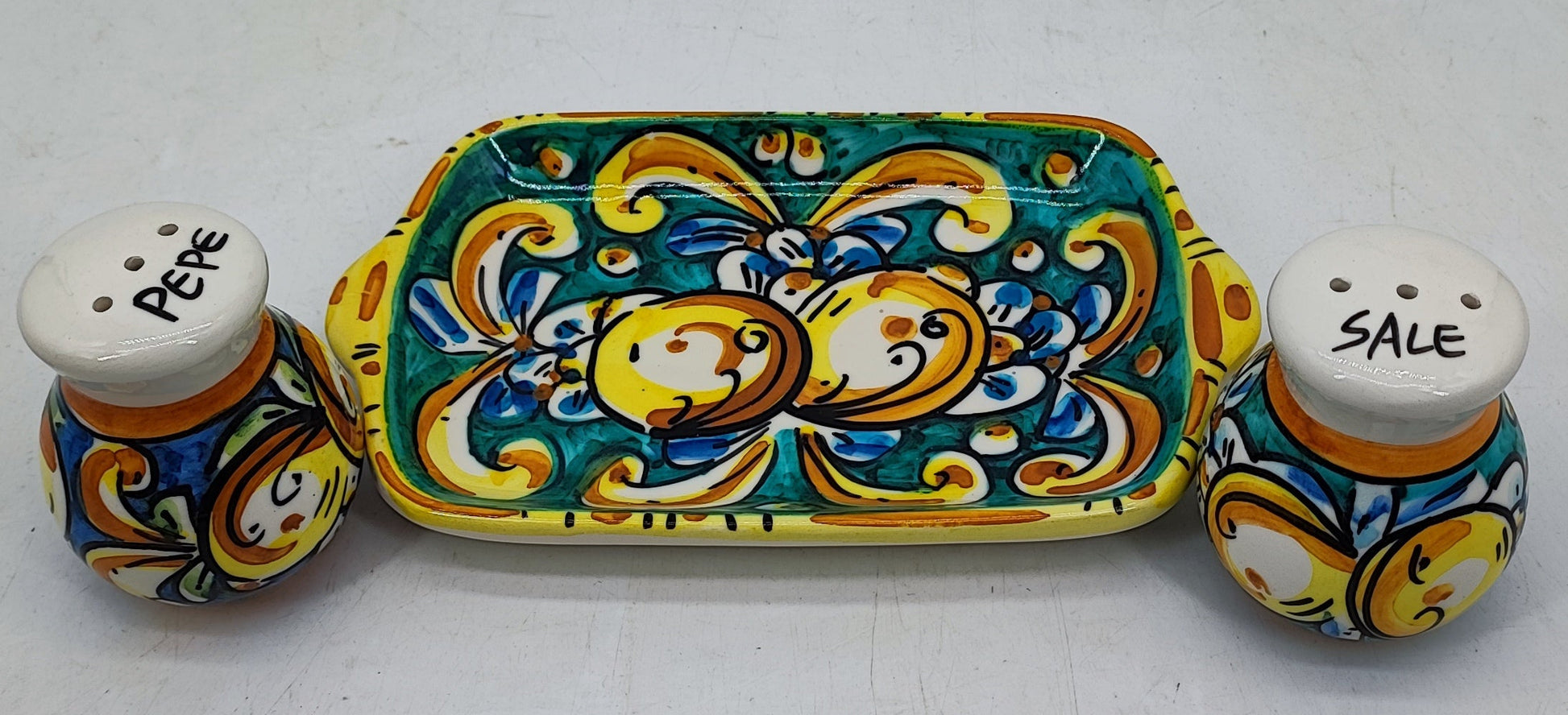 Front view of a turquoise-green Sicilian ceramic salt and pepper set with fruit decoration